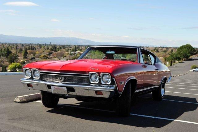 A red chevrolet chevelle is parked in a parking lot.