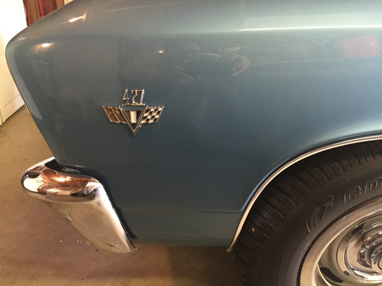 A blue classic car with a chrome emblem.
