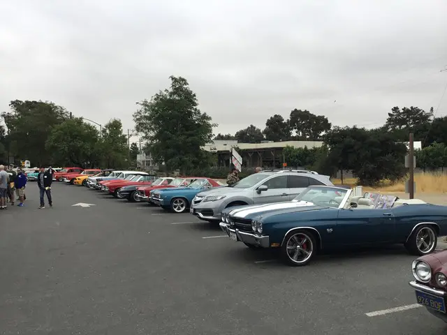 A line of classic cars parked in a parking lot.