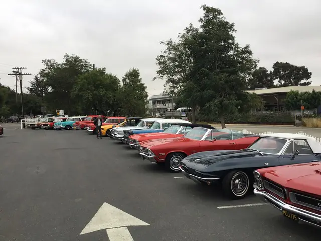 A row of classic cars parked in a parking lot.