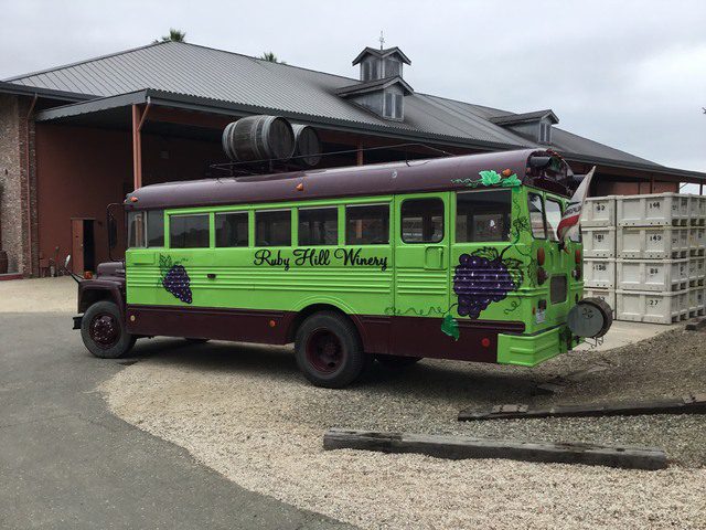 A green bus parked in front of a building.