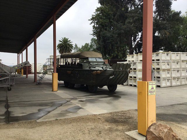 A military vehicle is parked in a warehouse.