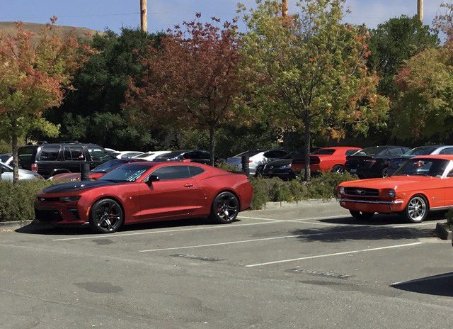 Two chevrolet camaros parked in a parking lot.