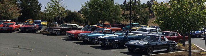 A group of classic cars parked in a parking lot.