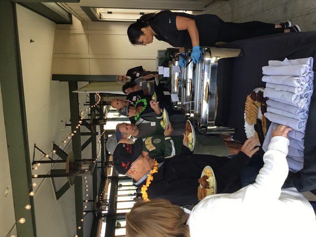 A group of people standing around a table with food.