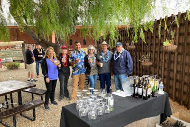 A group of people standing in front of a table with wine glasses.