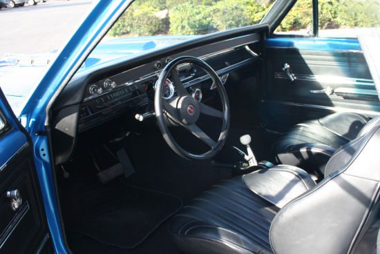 The interior of a blue car with leather seats and steering wheel.