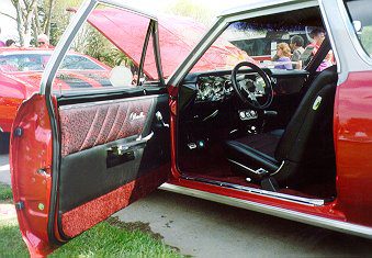 A red car with its door open at a show.