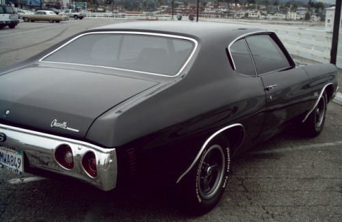 A black muscle car parked in a parking lot.