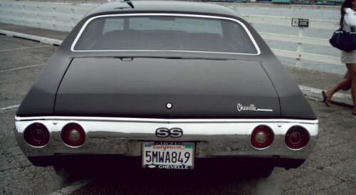 A black car with a license plate parked in a parking lot.