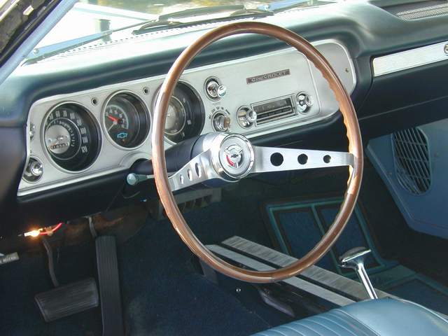The steering wheel and dashboard of a classic car.