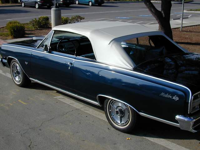 A blue and white classic car parked in a parking lot.