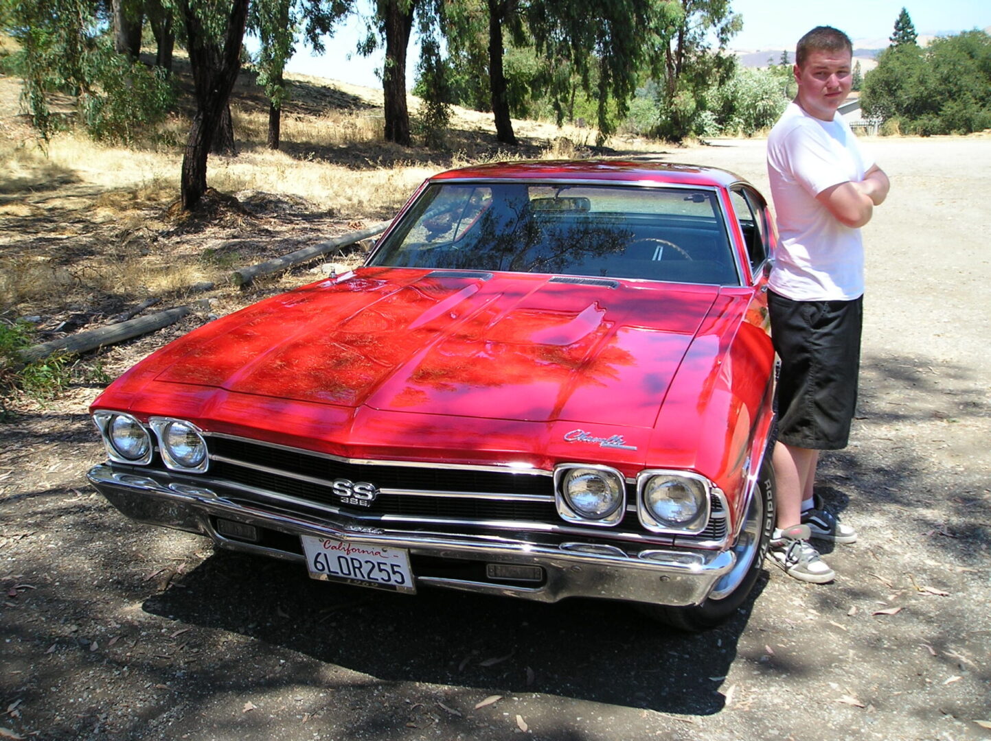 A man standing next to a red car.