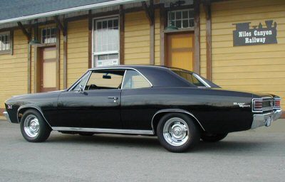 A black chevrolet chevelle parked in front of a building.