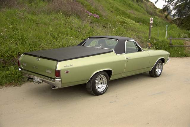 An old green car parked on the side of the road.