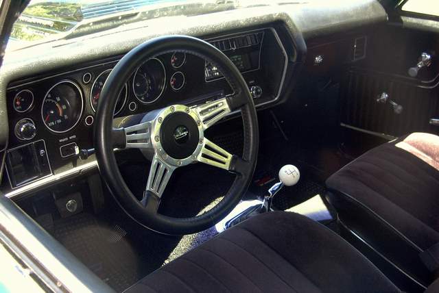 The interior of a classic car with a steering wheel and dashboard.