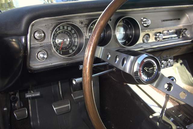 The interior of a classic car with a steering wheel and gauges.