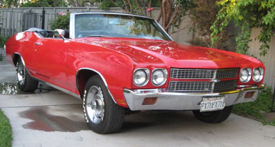 A red chevrolet chevelle parked in a driveway.