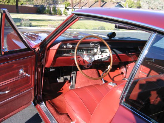 The interior of a red car with leather seats and steering wheel.