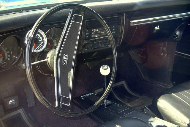 The interior of a classic car with a steering wheel and dashboard.