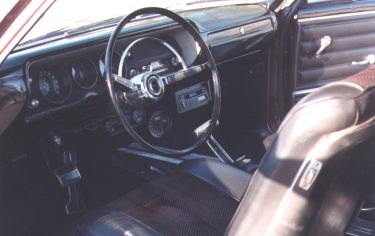 The interior of a classic car with leather seats and steering wheel.