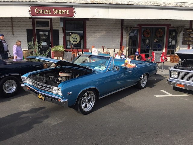 A blue chevrolet convertible parked in front of a coffee shop.