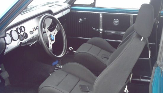 The interior of a blue car with black seats and steering wheel.