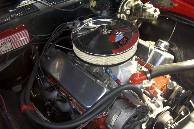 The engine compartment of a red car with a red engine.