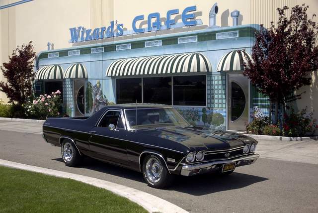 A black chevrolet el camino parked in front of a cafe.