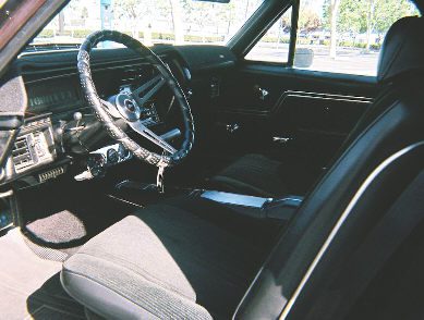 The interior of a classic car with leather seats and steering wheel.