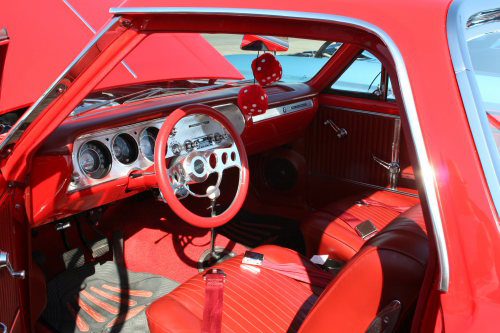 The interior of a red car with a steering wheel and steering wheel.