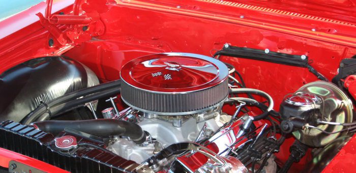 The engine compartment of a red pickup truck.