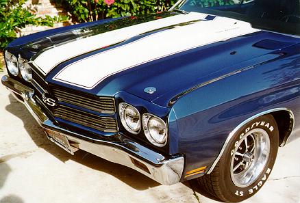 A blue and white chevrolet chevelle parked in front of a house.
