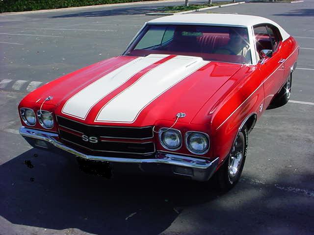 A red and white chevrolet chevelle parked in a parking lot.