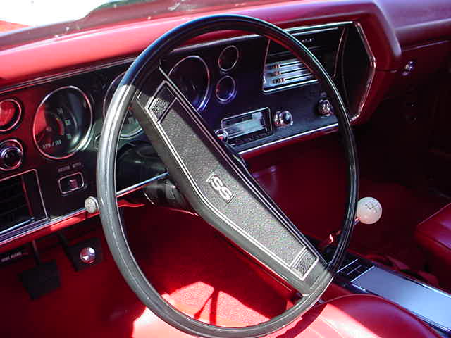 The interior of a red car with a steering wheel and dashboard.