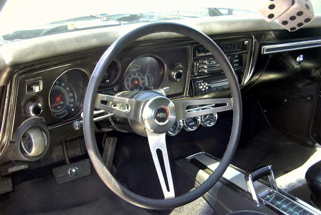 The interior of a classic car with a steering wheel and dashboard.