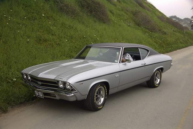 A silver chevrolet chevelle is parked on the side of the road.