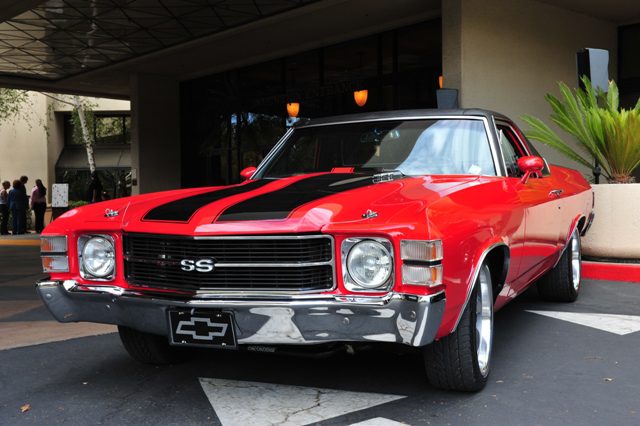 A red chevrolet chevelle parked in front of a building.